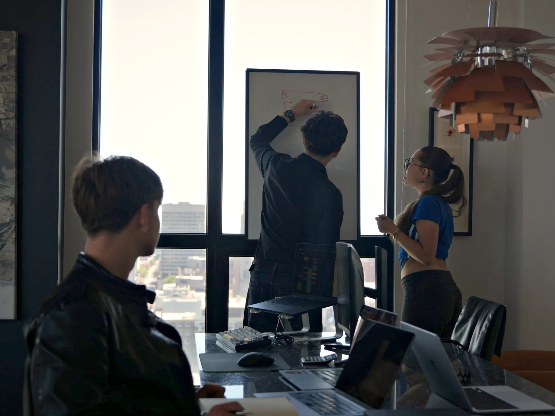 L’équipe de PULSE O devant un tableau blanc, en train de dessiner la structure d’une page.