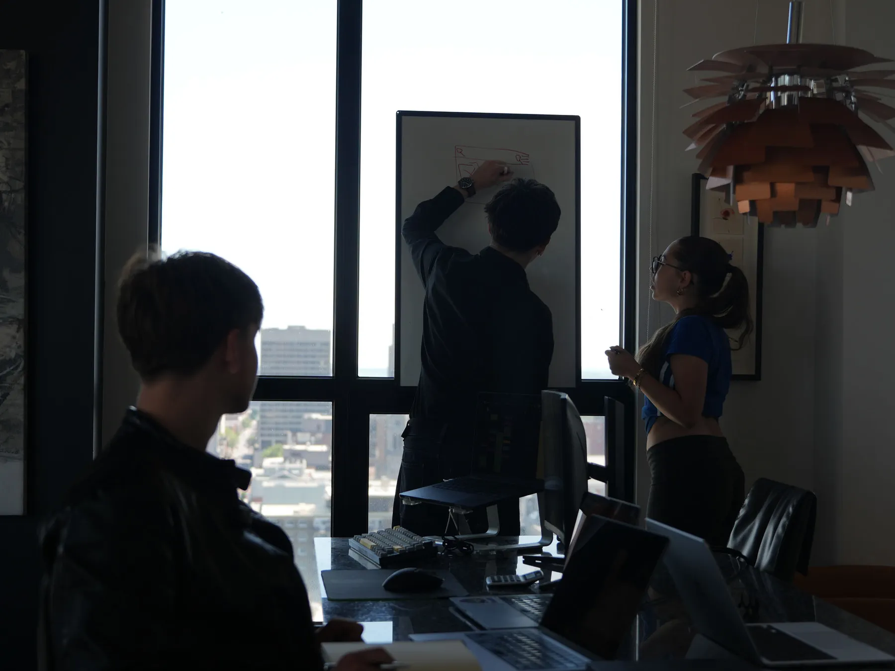 L’équipe de PULSE O devant un tableau blanc, en train de dessiner la structure d’une page.